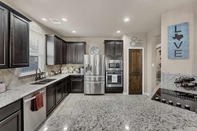 kitchen featuring tasteful backsplash, appliances with stainless steel finishes, light stone countertops, and sink