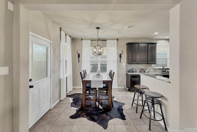 dining area with an inviting chandelier, sink, and light tile patterned floors