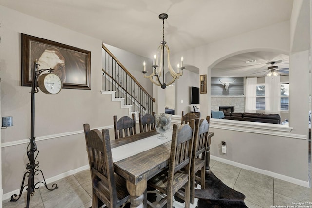 tiled dining room with ceiling fan with notable chandelier