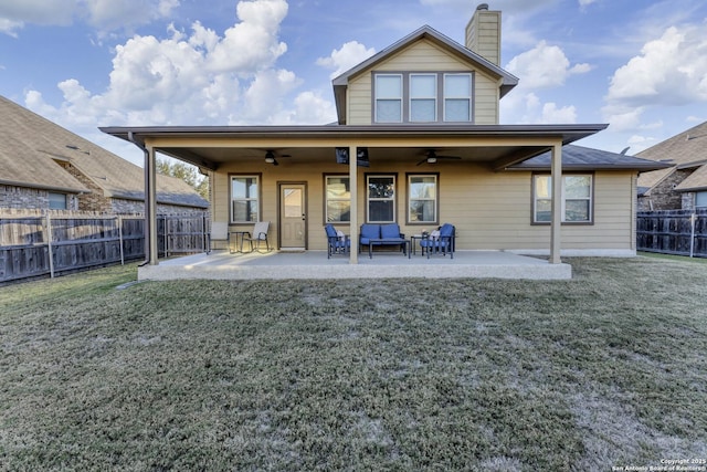 rear view of house with ceiling fan, a patio area, and a lawn