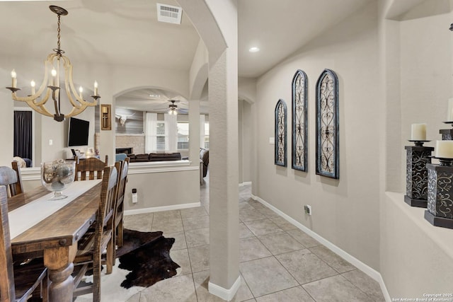 tiled dining space with ceiling fan with notable chandelier