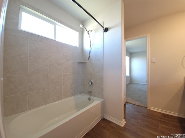 bathroom with plenty of natural light, tiled shower / bath combo, and wood-type flooring