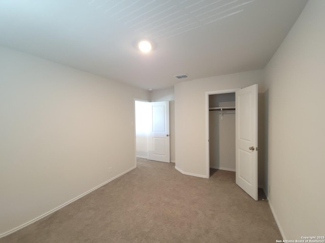 unfurnished bedroom featuring light colored carpet and a closet