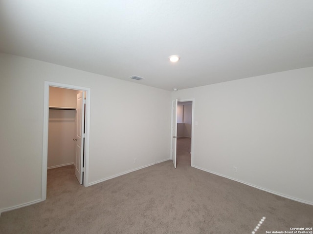 unfurnished bedroom featuring light colored carpet, a spacious closet, and a closet