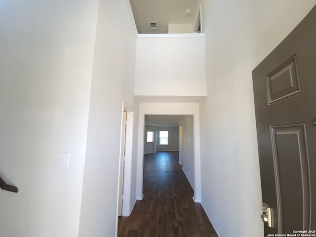 hall with dark hardwood / wood-style floors and a towering ceiling