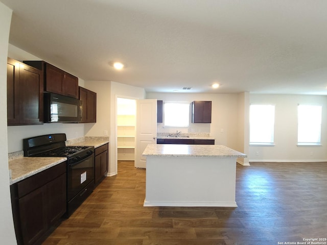 kitchen with dark wood-type flooring, sink, dark brown cabinets, a kitchen island, and black appliances