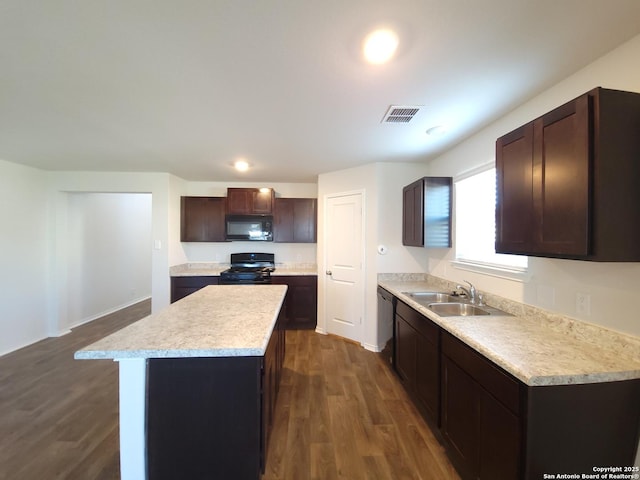 kitchen featuring dark wood-type flooring, a center island, sink, and black appliances