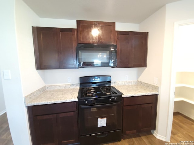 kitchen featuring dark brown cabinetry, light hardwood / wood-style flooring, and black appliances