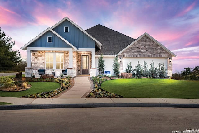 craftsman house featuring board and batten siding, brick siding, a lawn, and roof with shingles