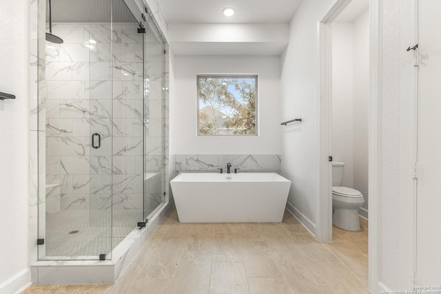 full bath featuring a freestanding tub, toilet, and a marble finish shower