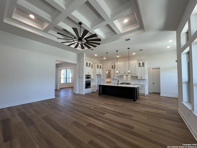 kitchen featuring glass insert cabinets, light countertops, an island with sink, and white cabinetry