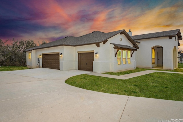 view of front of property featuring an attached garage, driveway, stucco siding, a front lawn, and a chimney