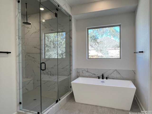 bathroom with a freestanding tub and a marble finish shower