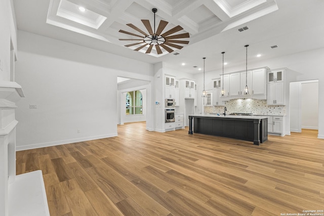 unfurnished living room with ceiling fan, visible vents, coffered ceiling, and light wood-style flooring