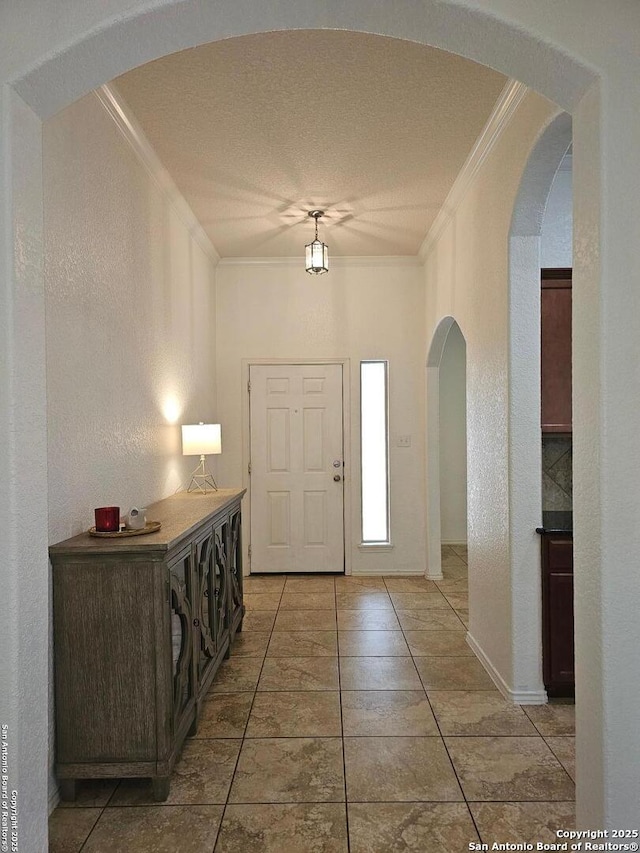 entrance foyer with crown molding and light tile patterned floors