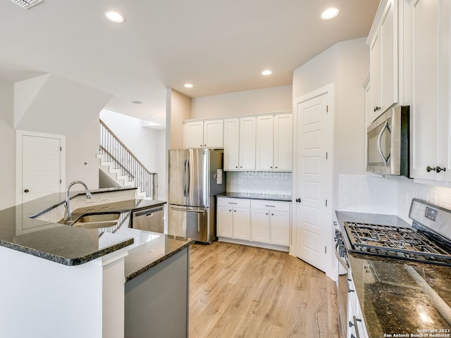 kitchen featuring white cabinetry, sink, light hardwood / wood-style floors, and appliances with stainless steel finishes