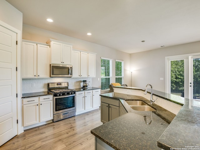 kitchen featuring sink, stainless steel appliances, dark stone counters, and white cabinets