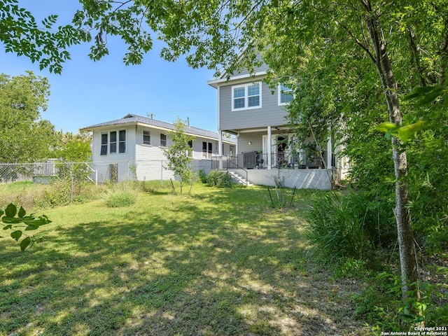 rear view of property featuring a lawn and covered porch