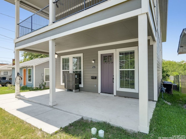 view of exterior entry with a balcony and a patio