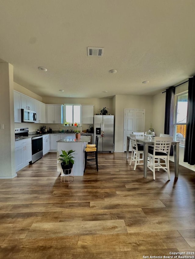 kitchen with a kitchen island, appliances with stainless steel finishes, white cabinets, and light hardwood / wood-style floors