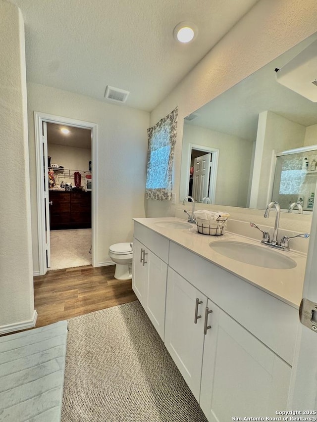 bathroom with vanity, wood-type flooring, a textured ceiling, toilet, and walk in shower