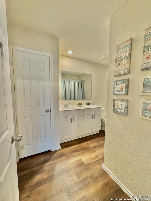 bathroom with vanity, hardwood / wood-style floors, a textured ceiling, and toilet