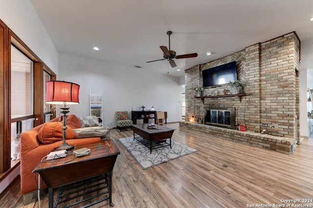 living room with a brick fireplace, light hardwood / wood-style floors, ceiling fan, and baseboard heating