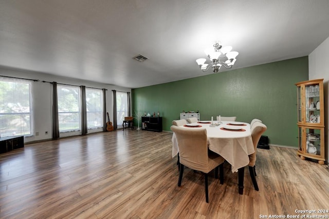 dining area featuring wood-type flooring and an inviting chandelier