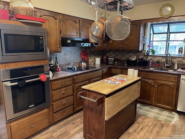 kitchen featuring sink, backsplash, exhaust hood, and appliances with stainless steel finishes