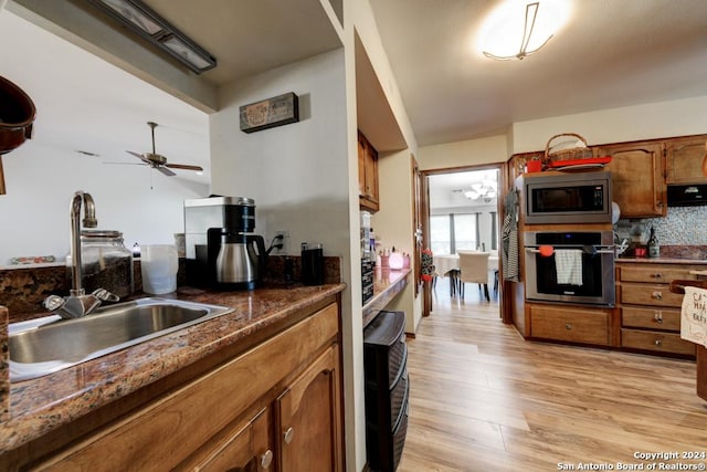 kitchen featuring sink, ceiling fan, range hood, stainless steel appliances, and light wood-type flooring