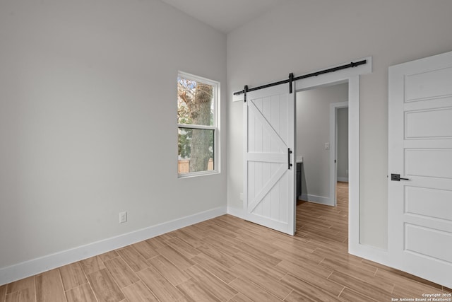 unfurnished bedroom featuring light hardwood / wood-style flooring and a barn door