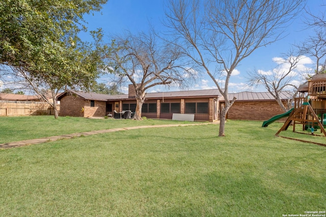 back of property featuring a yard, a sunroom, and a playground