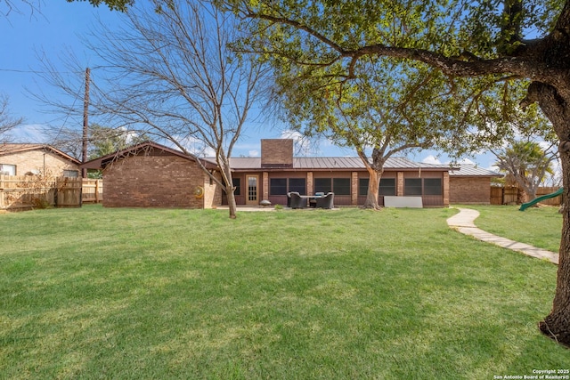 rear view of house with a yard and a sunroom