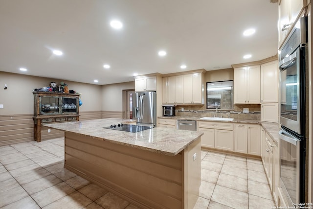 kitchen featuring sink, appliances with stainless steel finishes, a kitchen island, light stone countertops, and light tile patterned flooring