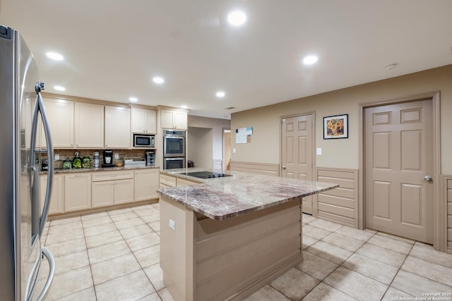 kitchen with light stone countertops, light tile patterned floors, stainless steel appliances, and a center island with sink