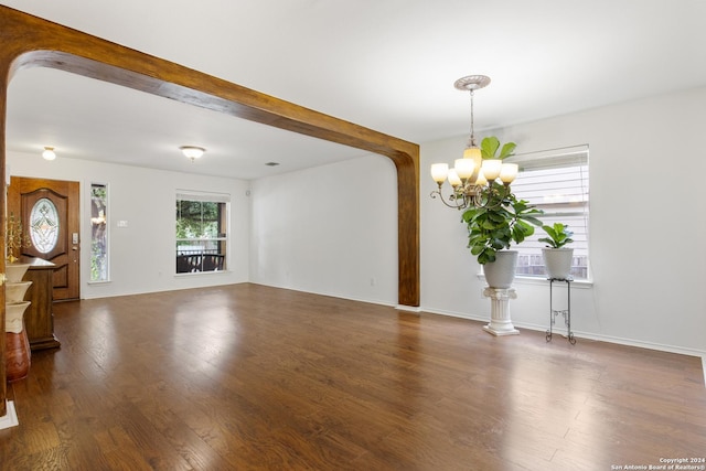 unfurnished living room with dark hardwood / wood-style floors, a notable chandelier, and beam ceiling