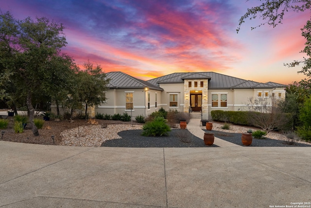 view of front of property with metal roof, a standing seam roof, and stucco siding