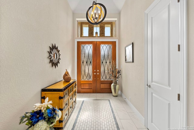 entrance foyer featuring baseboards, french doors, and a notable chandelier