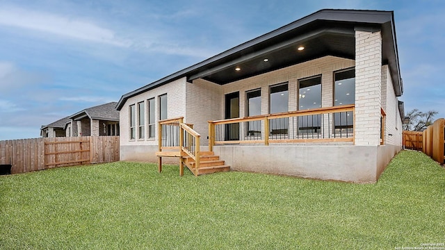 rear view of house featuring brick siding, a lawn, and a fenced backyard