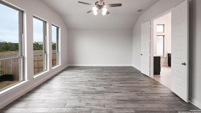 unfurnished room with vaulted ceiling, baseboards, visible vents, a ceiling fan, and wood finished floors