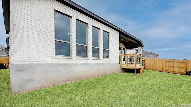 view of side of home with brick siding, a yard, and fence