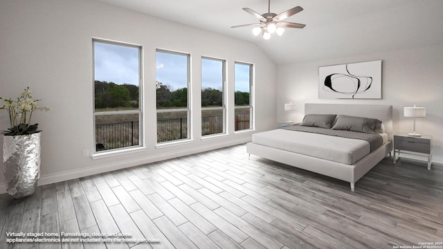 bedroom featuring lofted ceiling, baseboards, and wood finished floors