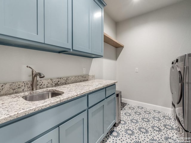 clothes washing area with sink, washer and clothes dryer, and cabinets