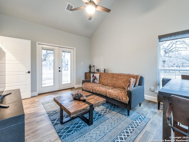 living room with hardwood / wood-style flooring, high vaulted ceiling, french doors, and ceiling fan