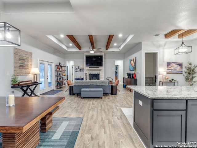 kitchen with gray cabinetry, hanging light fixtures, beam ceiling, light stone countertops, and french doors