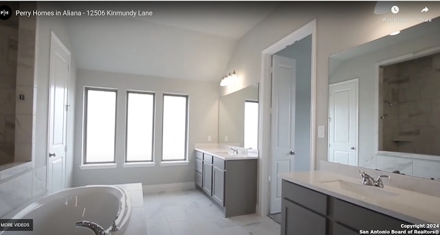 bathroom featuring vanity, lofted ceiling, and a tub