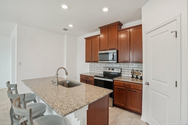 kitchen featuring light stone counters, sink, a kitchen bar, and appliances with stainless steel finishes