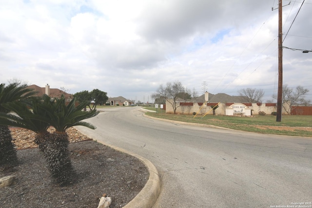 view of asphalt street featuring curbs