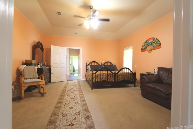 bedroom with carpet flooring, a tray ceiling, and a ceiling fan