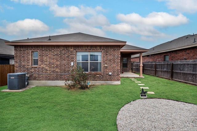 rear view of property with cooling unit, a yard, and a patio